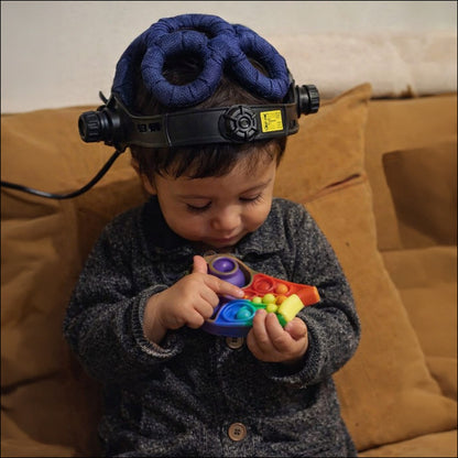 Young child sitting on a sofa wearing the QuantumMind TMS Helmet
